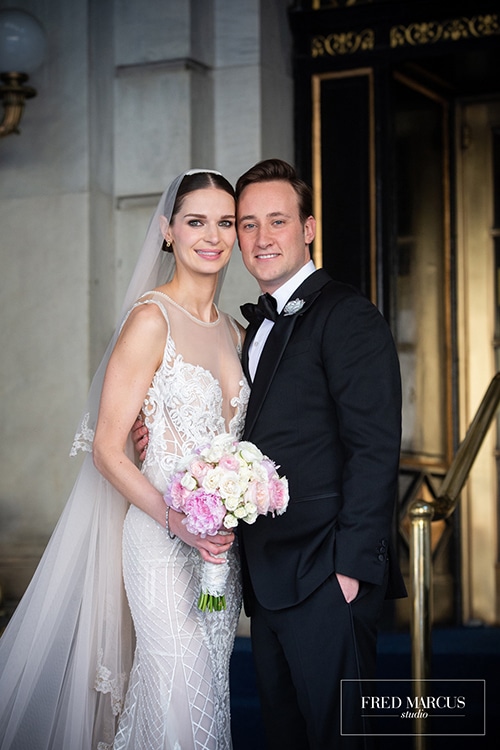 bride and groom smile in front of hotel entrance
