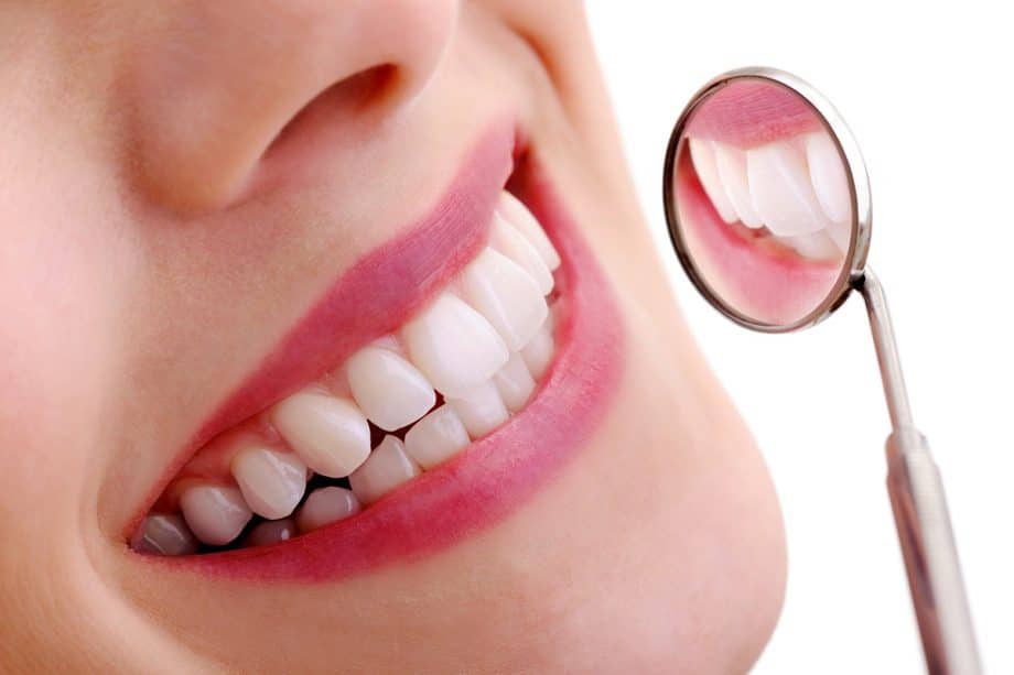 a woman's smiling teeth reflected in dental mirror