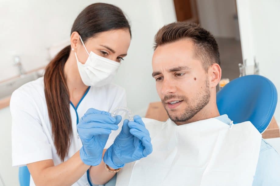man in dental chair looks at Invisalign tray
