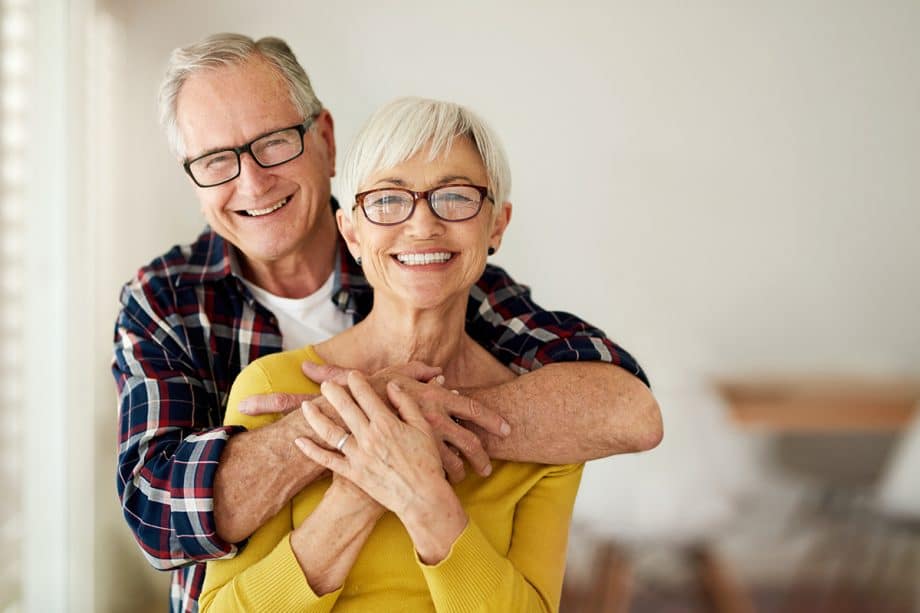 smiling man and woman embrace in front of blurred background