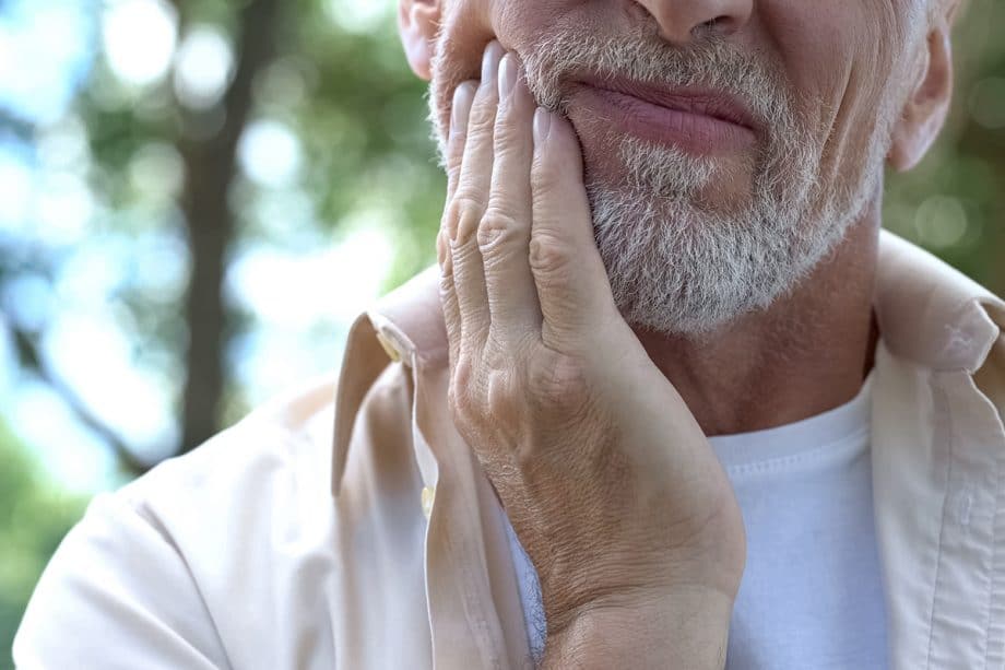 a man holding his jaw due to tooth pain