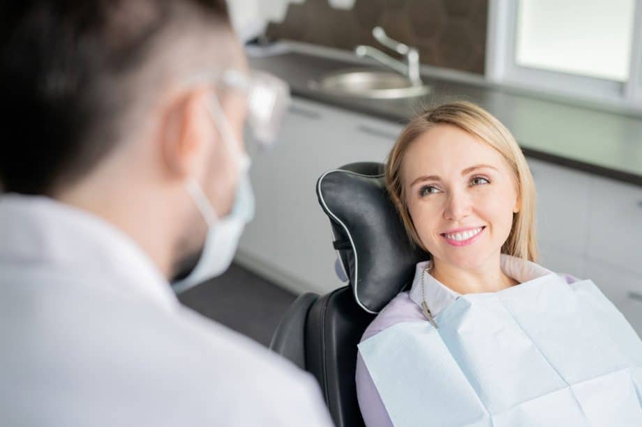 woman in dental chair smiles at dentist